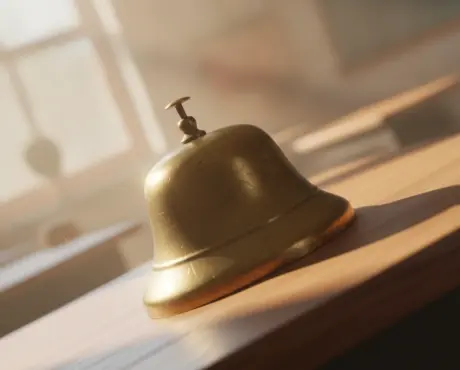 Macro close-up of a brass preschool hand bell mid-ring in morning light, evoking operational intelligence alerts.